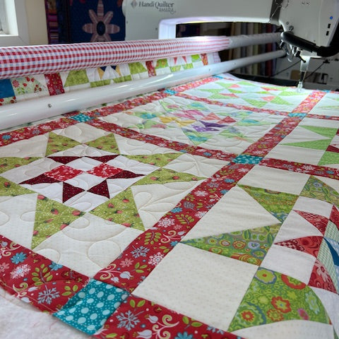 Colorful quilt with various patterns next to a sewing machine.